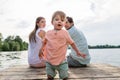 Family sitting on jetty of pond or lake in summer Royalty Free Stock Photo