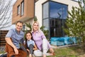 Family sitting on lawn in backyard, big modern house on background Royalty Free Stock Photo