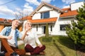 Family sitting on lawn in backyard, big modern house on background Royalty Free Stock Photo