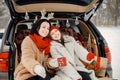 Family sitting in open car& x27;s trunk at winter park and drink a tea Royalty Free Stock Photo