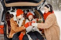 Family sitting in open car& x27;s trunk at winter park and drink a tea Royalty Free Stock Photo