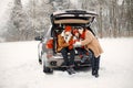 Family sitting in open car's trunk at winter park and drink a tea Royalty Free Stock Photo