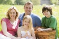 Family sitting outdoors with picnic basket smiling Royalty Free Stock Photo