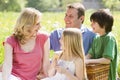 Family sitting outdoors with picnic basket smiling Royalty Free Stock Photo