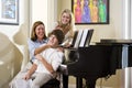 Family sitting on piano bench, mother teasing son