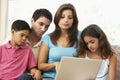 Family Sitting On Sofa At Home With Laptop Royalty Free Stock Photo