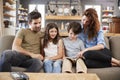 Family Sitting On Sofa In Lounge Reading Book Together Royalty Free Stock Photo