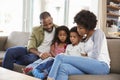 Family Sitting On Sofa In Lounge Reading Book Together Royalty Free Stock Photo