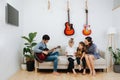 Family sitting on a sofa. Mom and kids looking on a tablet, dad plays guitar Royalty Free Stock Photo
