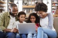 Family Sitting On Sofa In Open Plan Lounge Using Laptop Royalty Free Stock Photo