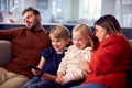 Family Sitting On Sofa Watching TV Together As Parents Fall Asleep Royalty Free Stock Photo