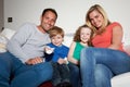 Family Sitting On Sofa Watching TV Together