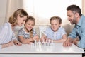 Family sitting at table and playing with domino pieces Royalty Free Stock Photo