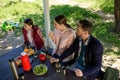 Family Are Sitting By The Table In Wooden Gazebo In Park While Looking On The Left Side. Royalty Free Stock Photo