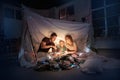 Family sitting in a teepee, reading stories with the flashlight Royalty Free Stock Photo