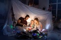 Family sitting in a teepee, reading stories with the flashlight Royalty Free Stock Photo