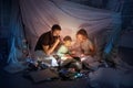 Family sitting in a teepee, reading stories with the flashlight Royalty Free Stock Photo