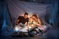 Family sitting in a teepee, reading stories with the flashlight Royalty Free Stock Photo