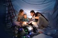 Family sitting in a teepee, reading stories with the flashlight Royalty Free Stock Photo