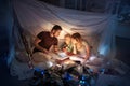 Family sitting in a teepee, reading stories with the flashlight Royalty Free Stock Photo