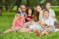 Family of six sits on rag matting and eats fruits