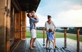 Family with small children playing in rain on patio by wooden cabin, holiday in nature concept. Royalty Free Stock Photo