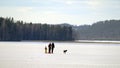 A family with a small toddler and a dog playing on a frozen lake.