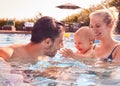 Family With Son And Baby Daughter Having Fun On Summer Vacation Splashing In Outdoor Swimming Pool Royalty Free Stock Photo
