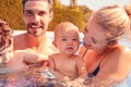 Family With Son And Baby Daughter Having Fun On Summer Vacation Splashing In Outdoor Swimming Pool Royalty Free Stock Photo