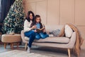 Family spending time at home for Christmas and New year holidays. Mother and daughter reading book by Christmas tree Royalty Free Stock Photo