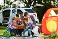 Family spending time together. Mother reading book outdoor with kids against their suv car Royalty Free Stock Photo