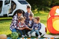 Family spending time together. Mother reading book outdoor with kids against their suv car Royalty Free Stock Photo