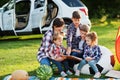 Family spending time together. Mother reading book outdoor with kids against their suv car Royalty Free Stock Photo