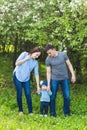 Family spending time together in the park in spring time. Mother, child and father in blooming garden. Royalty Free Stock Photo