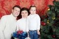 Family stand with gifts near Christmas tree at home. Royalty Free Stock Photo