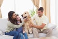 Family stroking dog while sitting on sofa Royalty Free Stock Photo