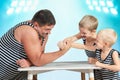 Family of strongman. The father of two sons in vintage costume of athletes compete in arm wrestling. Family look. Royalty Free Stock Photo