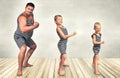 Family of strongman. The father of two sons in vintage costume of athletes perform strength exercises. Family look. Royalty Free Stock Photo