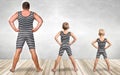 Family of strongman. The father of two sons in vintage costume of athletes perform strength exercises. Family look. Royalty Free Stock Photo