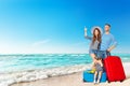 Family on Summer Holiday Vacations. Happy Smiling Parents with Kid sitting on Stack of Suitcases on Sea Side Sand Beach Royalty Free Stock Photo