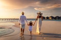 A family on summer holidays walks down a beach during sunset Royalty Free Stock Photo