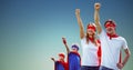 Family in superhero costumes standing with arms raised Royalty Free Stock Photo