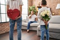 Family surprise father with gift and flowers on back at home