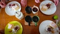 Family sweet breakfast. On the wooden table: custard cake, ice cream in a waffle cone, ice cream sprinkled with chocolate chips,