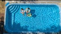 Family in swimming pool aerial drone view from above, happy mother and kids swim on inflatable ring donuts and have fun in water Royalty Free Stock Photo