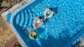 Family in swimming pool aerial drone view from above, happy mother and kids swim on inflatable ring donuts and have fun in water Royalty Free Stock Photo