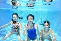 Family swims in swimming pool under water, happy active mother and children have fun underwater, fitness and sport with kids