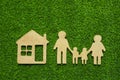 Family symbols and houses made of natural wood on the background of green grass symbolize the eco-house.