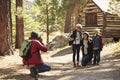 Family taking a photo in front of a log cabin in a forest Royalty Free Stock Photo