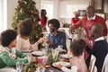 Family talking and raising glasses at the dinner table during a multi generation, mixed race family Christmas celebration Royalty Free Stock Photo